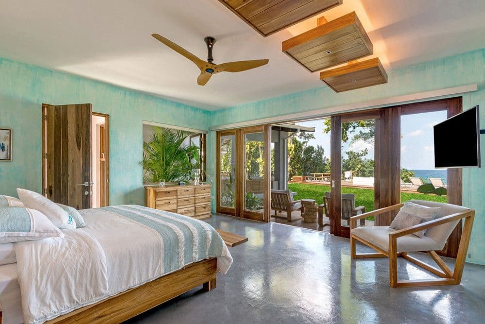 Guest bedroom with a soft turquoise wall opening to a sea-view terrace at Promiseas