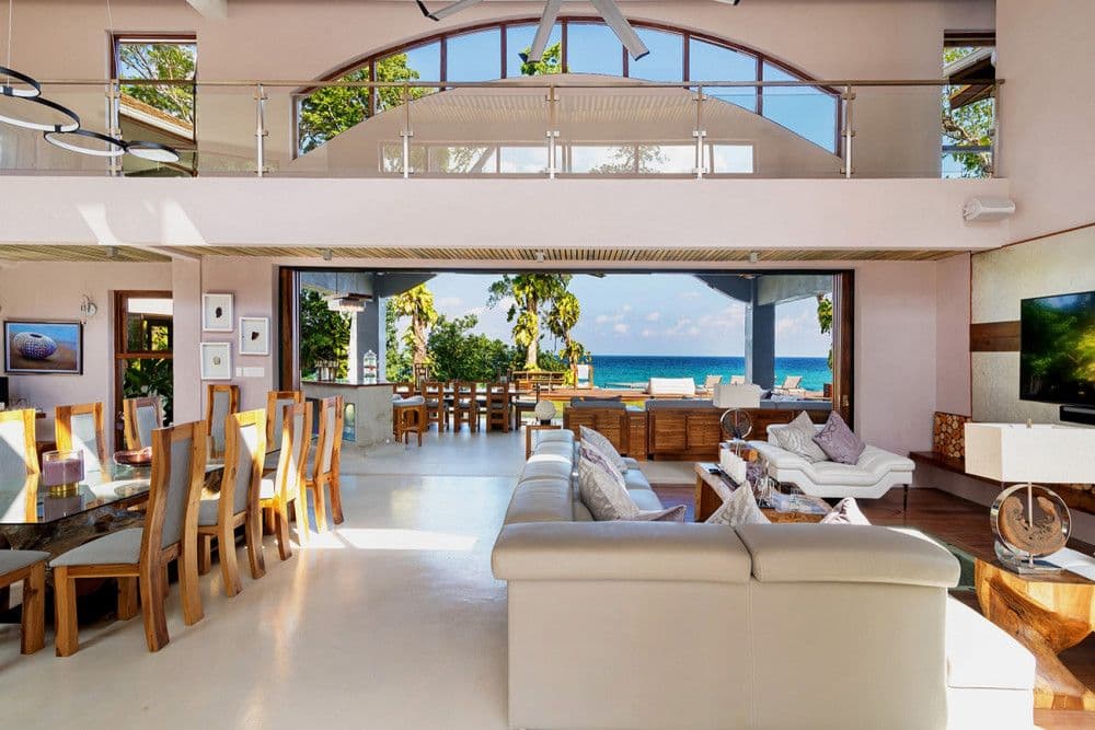 Double-height open-plan living and dining area opening to the sea at Promiseas