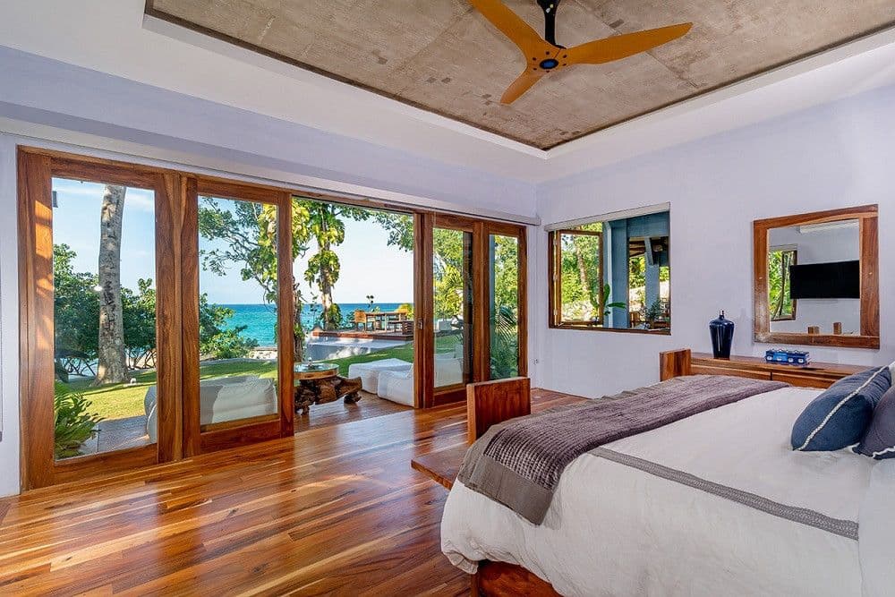 Master bedroom with teak floors and sliding glass to the lawn and sea at Promiseas