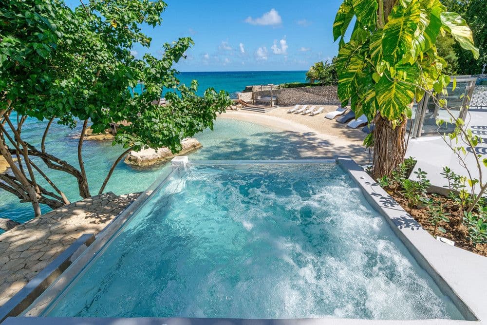 Infinity pool above a private sandy cove and turquoise sea at Promiseas, Ocho Rios