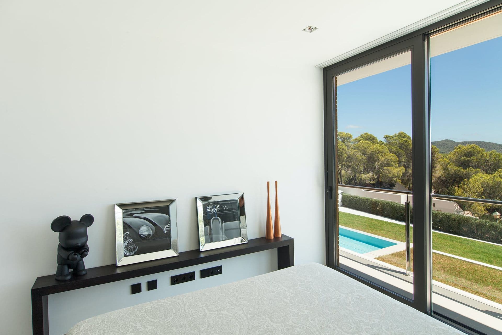 Bedroom with dark wood furniture and a large window framing the garden