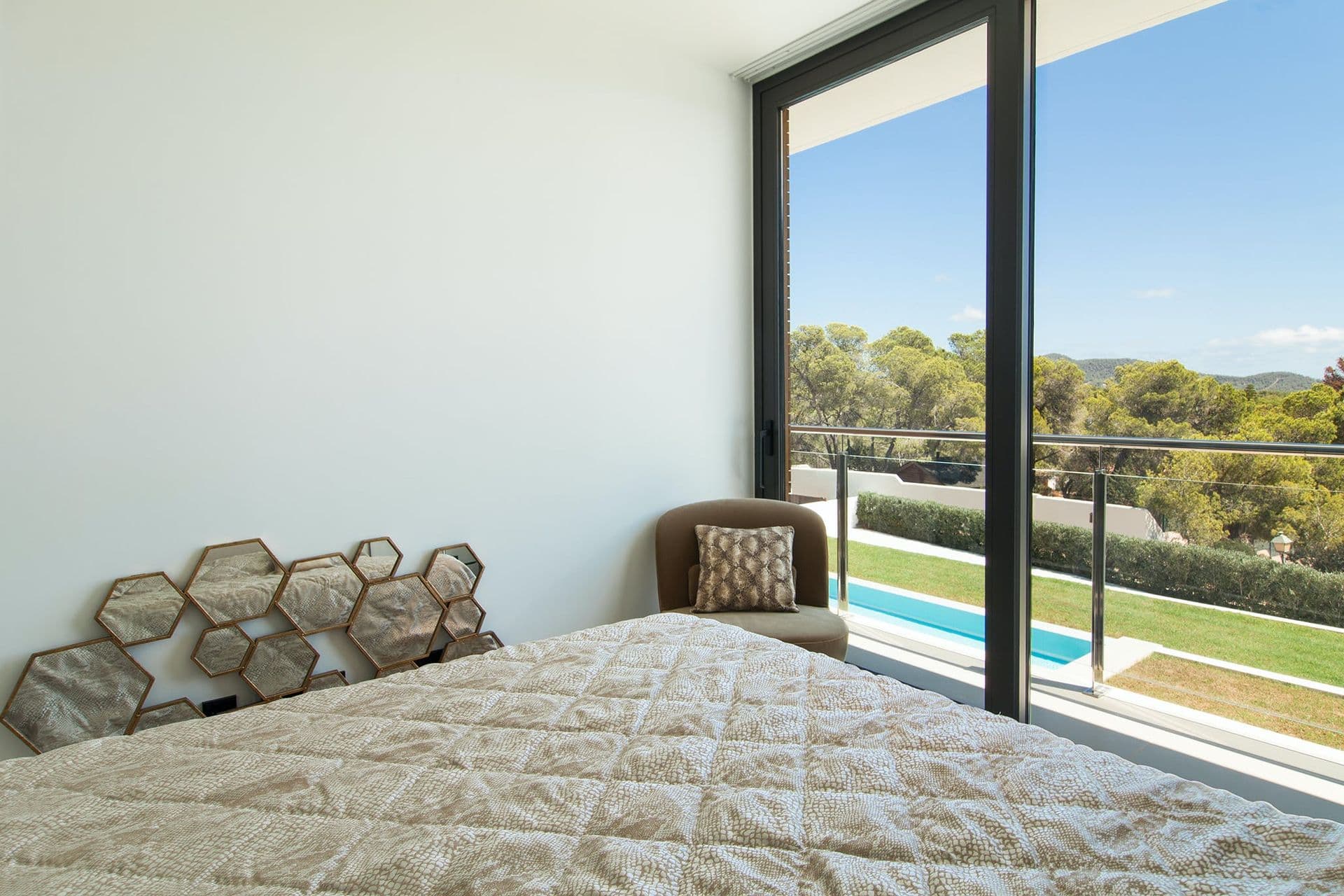 Bedroom with a textured honeycomb headboard and glass doors to the pool terrace