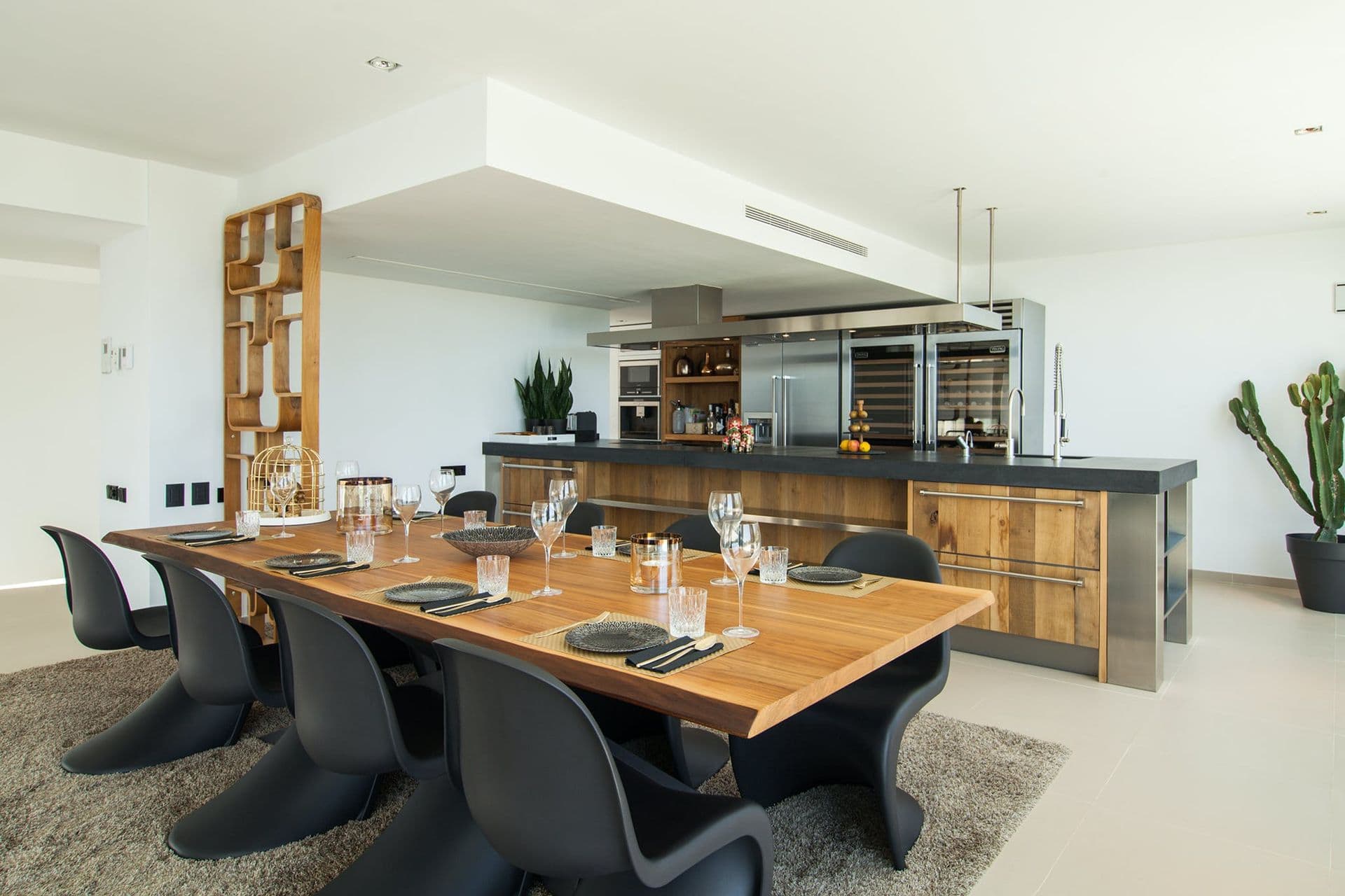 Dining table with black chairs adjacent to a built-in bar and wine display