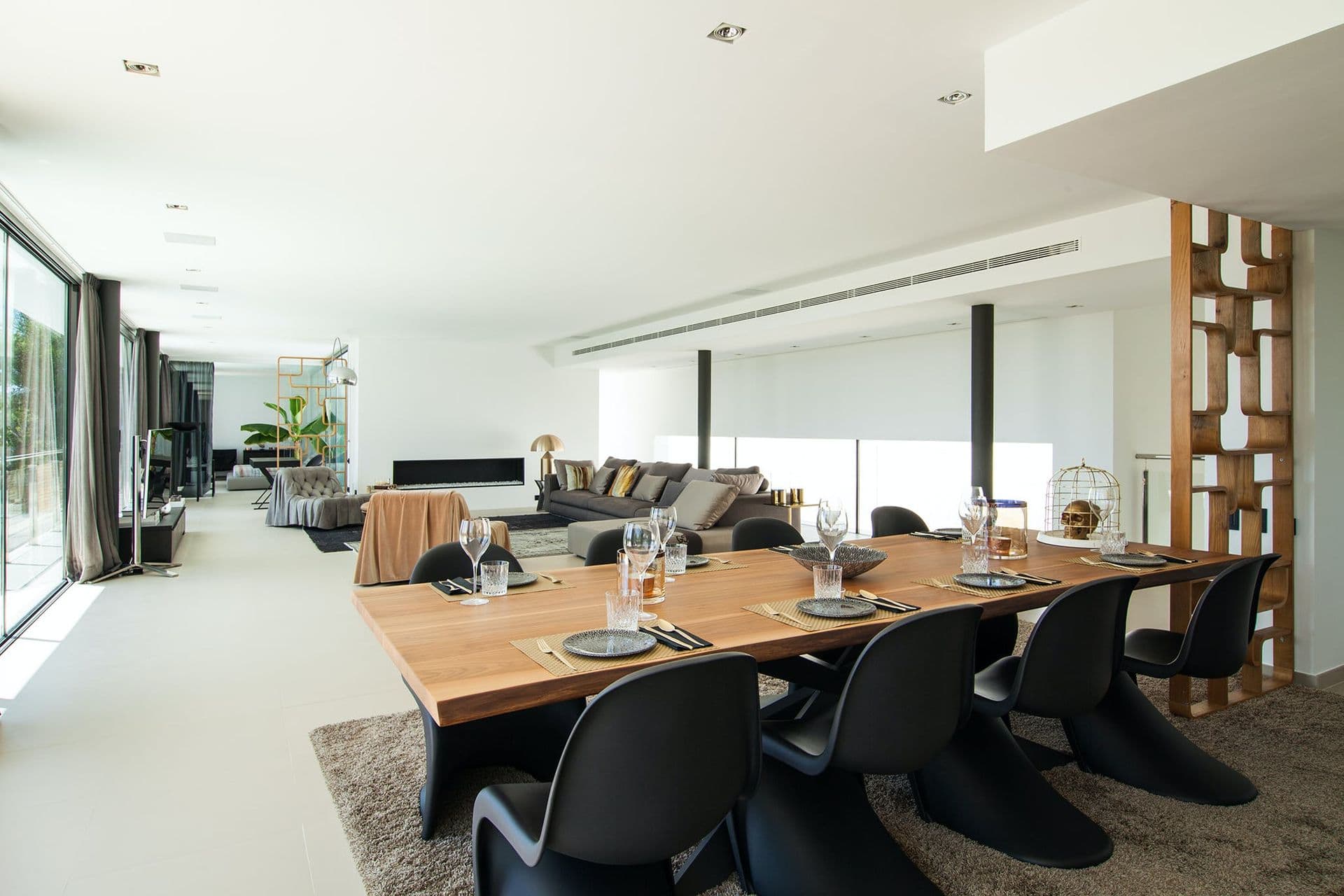 Long wooden dining table seating ten beside floor-to-ceiling windows
