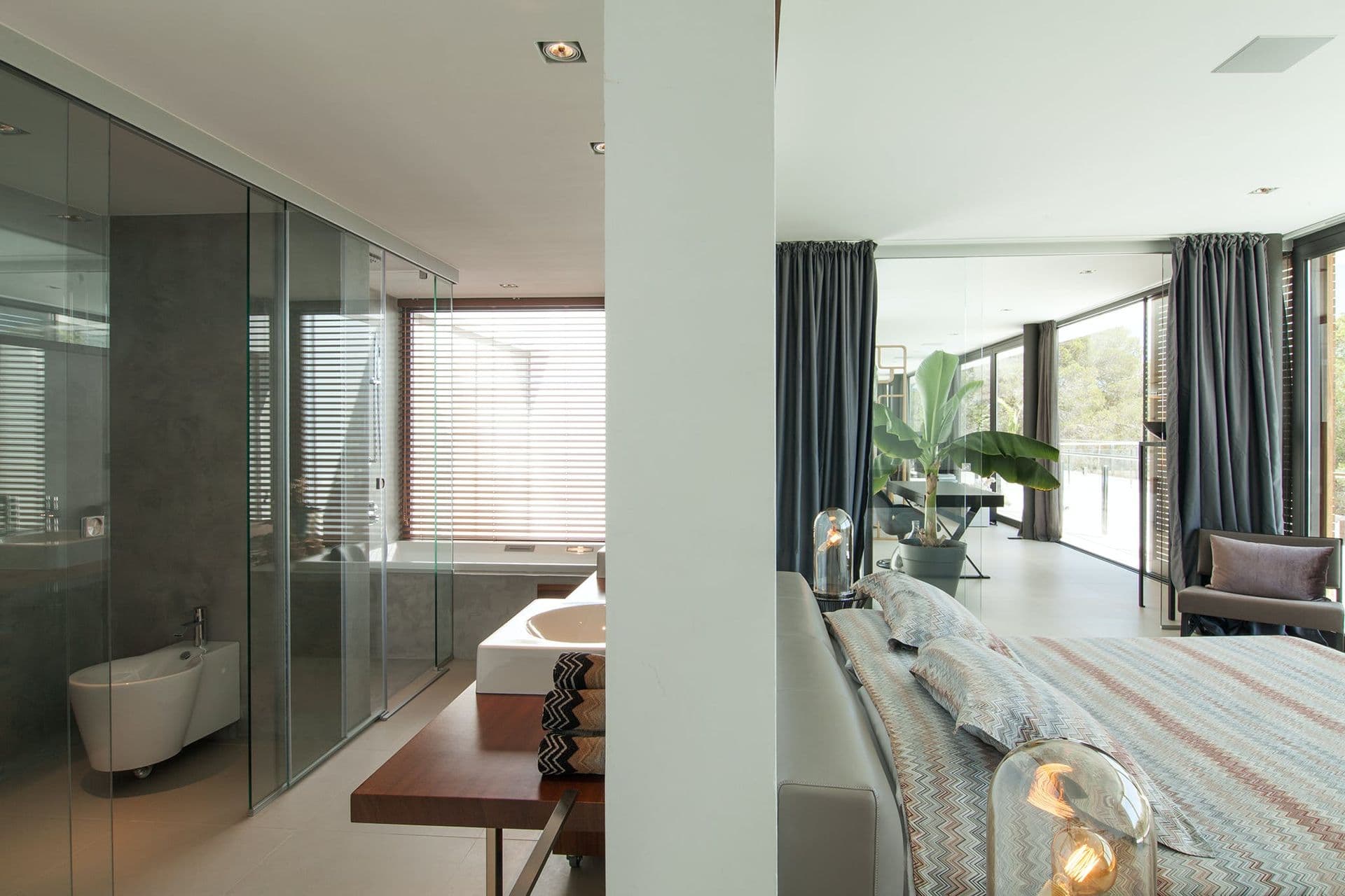 Glass-partitioned ensuite bathroom adjoining the bedroom, with countryside views