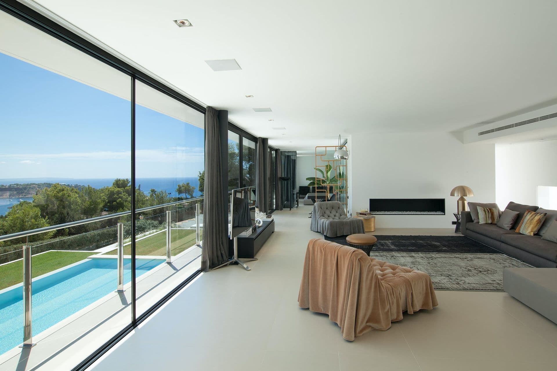Corner sofa lounge with panoramic glass walls overlooking the pool and sea