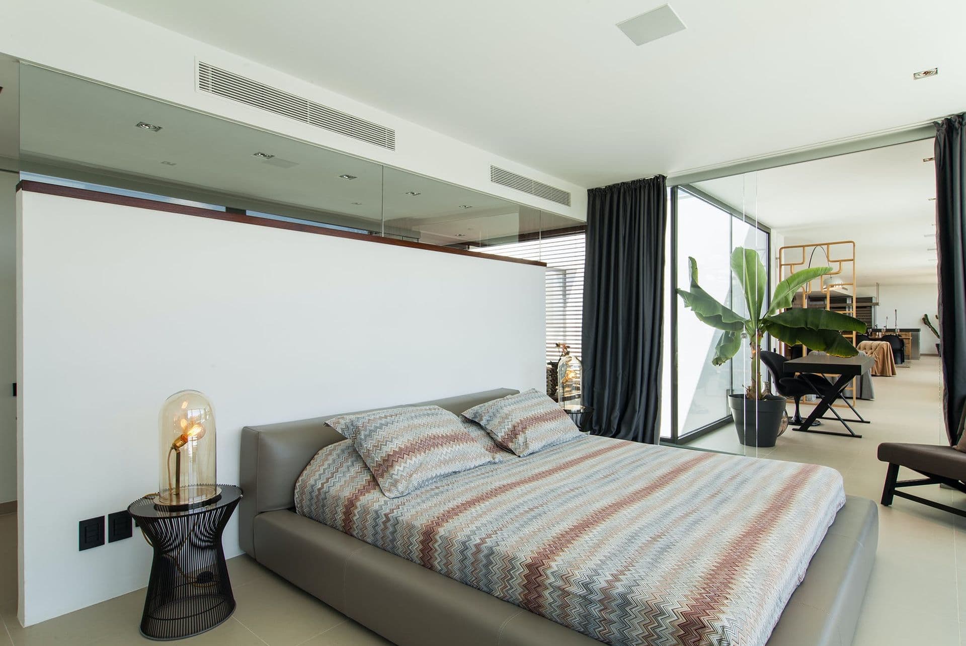 Bedroom with striped throw and glass doors opening onto a private terrace
