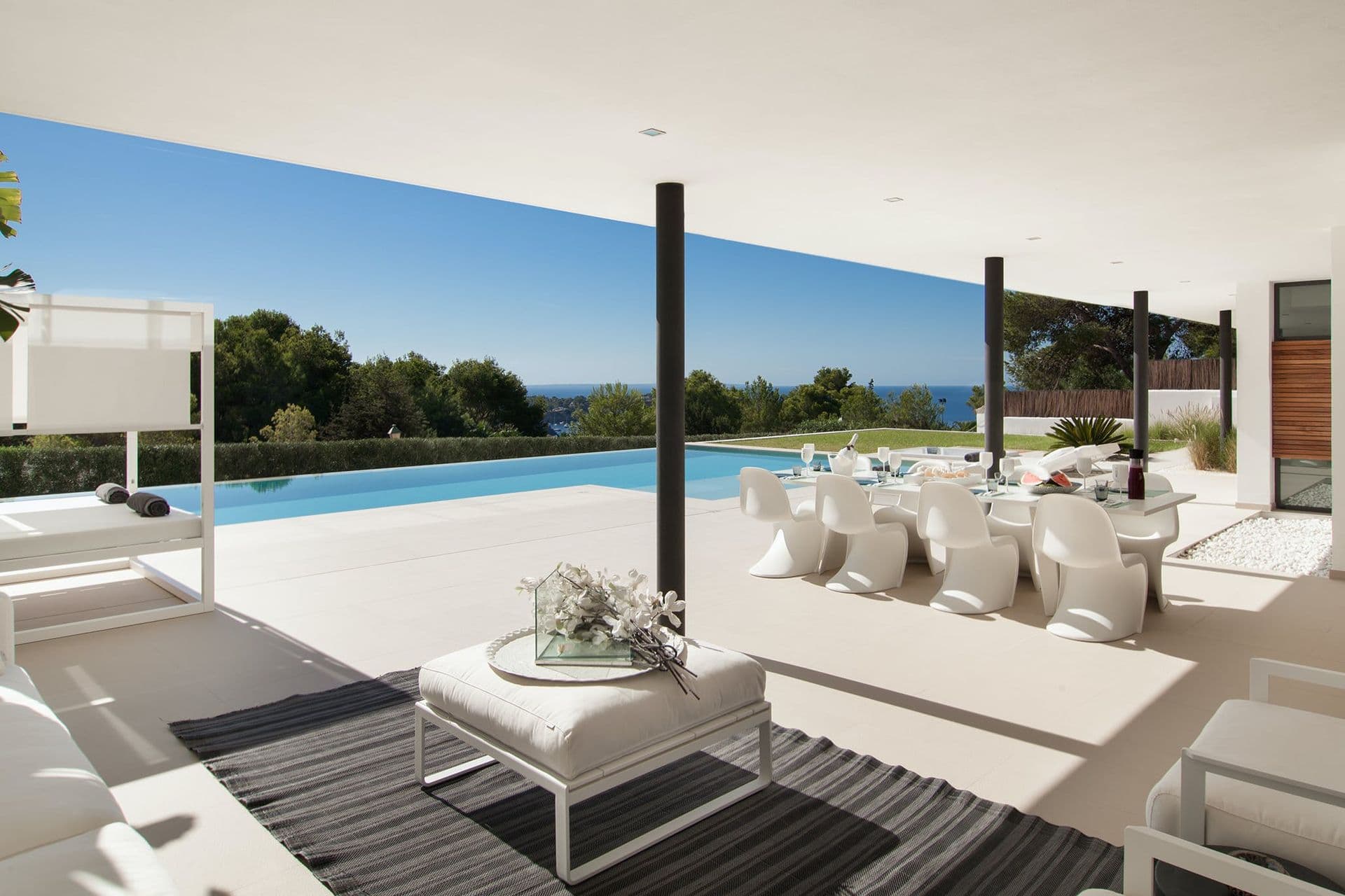 Poolside terrace with lounge seating and dining table under a covered walkway