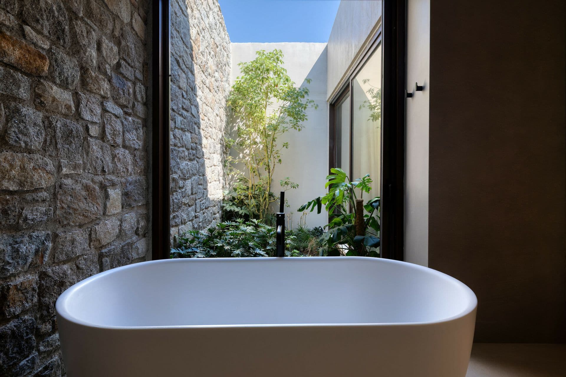 Freestanding bathtub in a private stone courtyard at Ocean Breeze & Sea Views