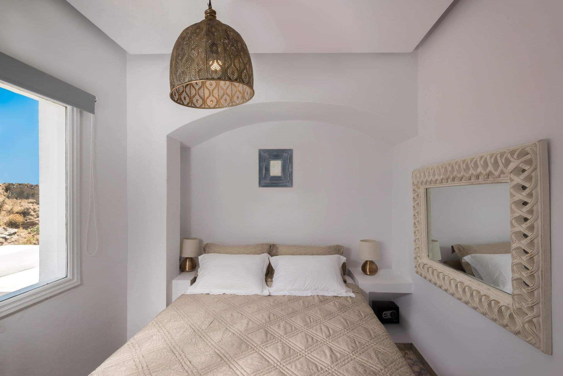 Bedroom set within a whitewashed arched alcove with carved mirror at Hand of Hygieia