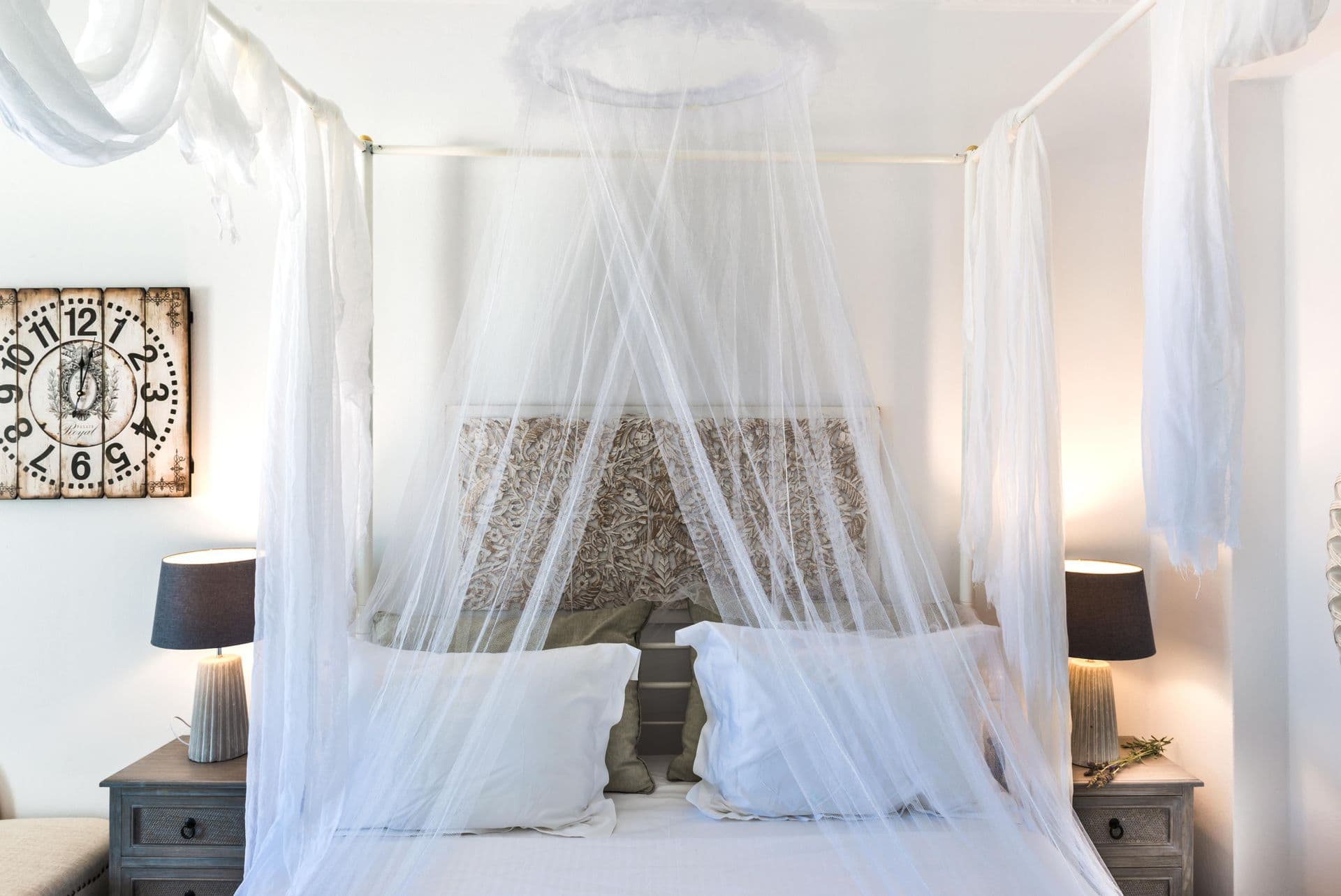 Bedroom with a four-poster bed draped in white mosquito netting at Hand of Hygieia