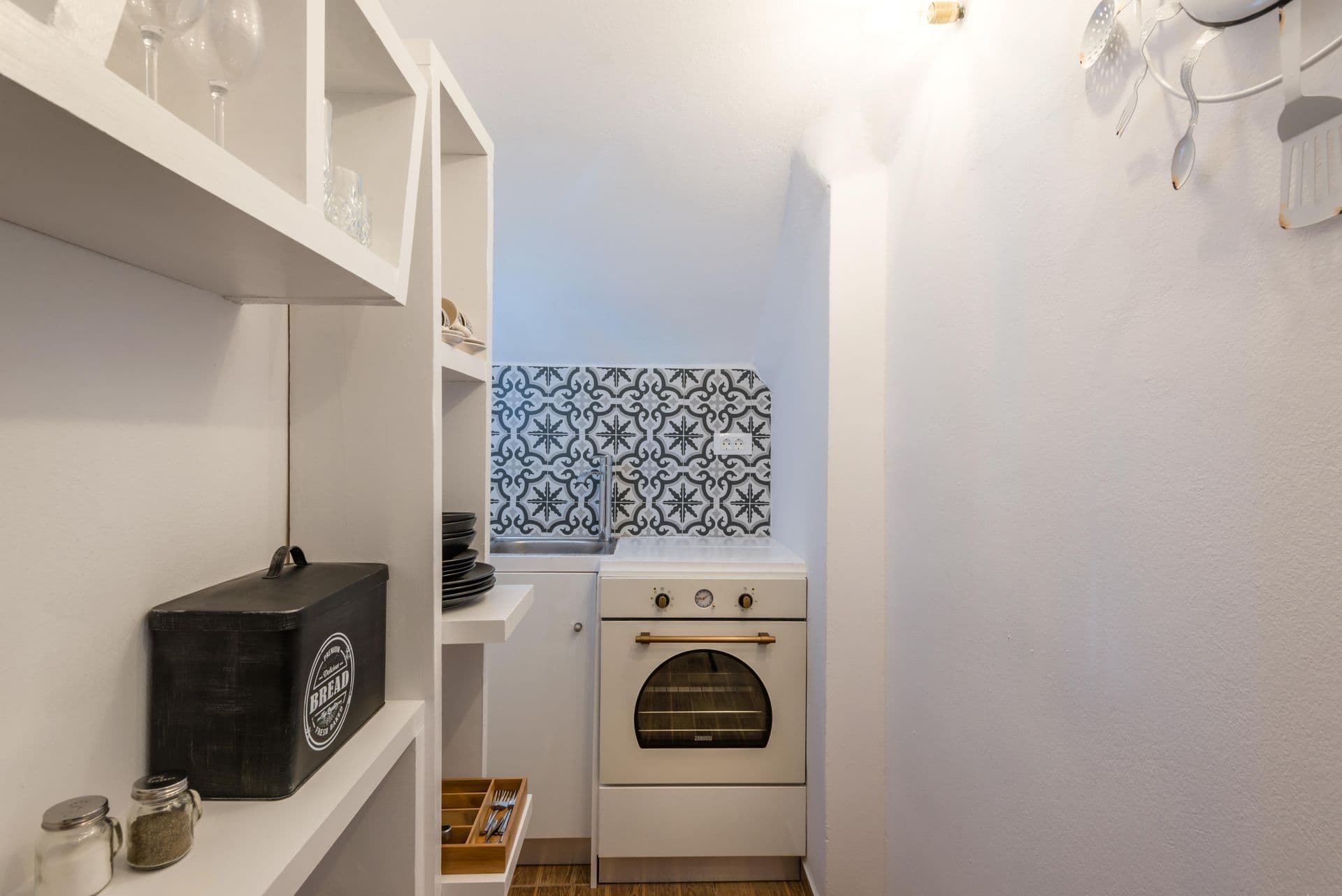 Kitchen with white cabinetry and patterned tile backsplash at Hand of Hygieia