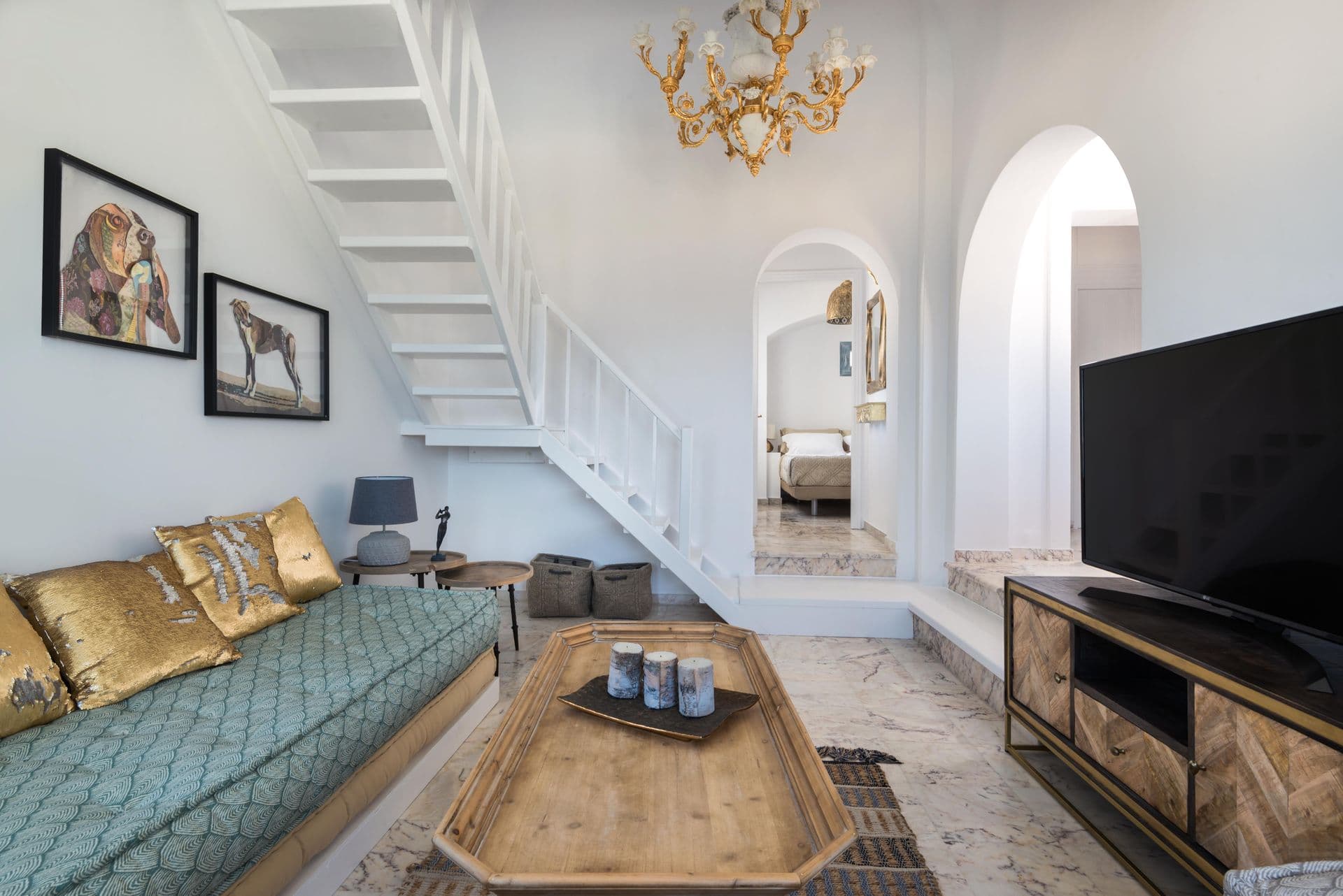 Living room with green velvet sofas and a spiral staircase at Hand of Hygieia