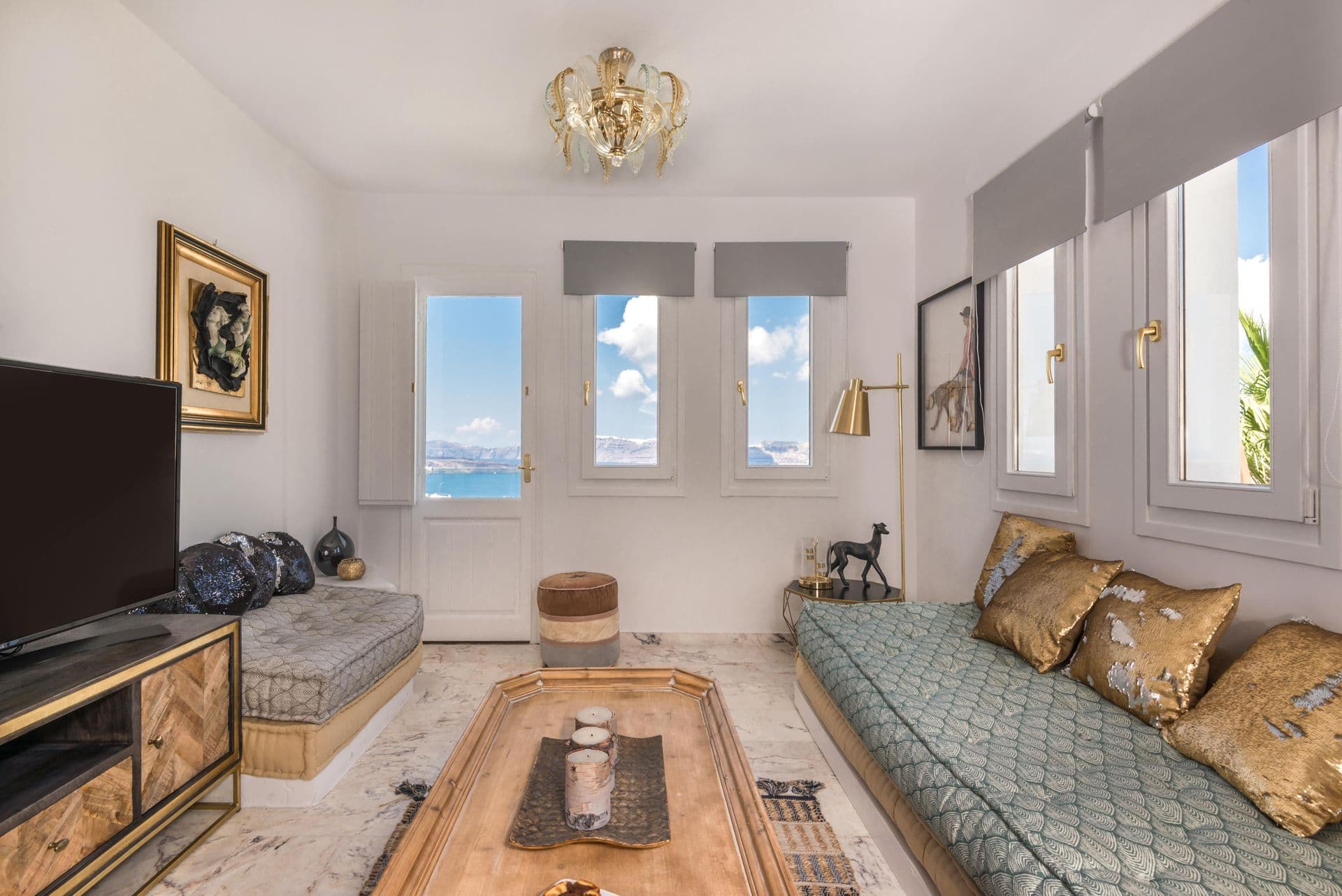 Living room seating area with television and gold-toned decor at Hand of Hygieia
