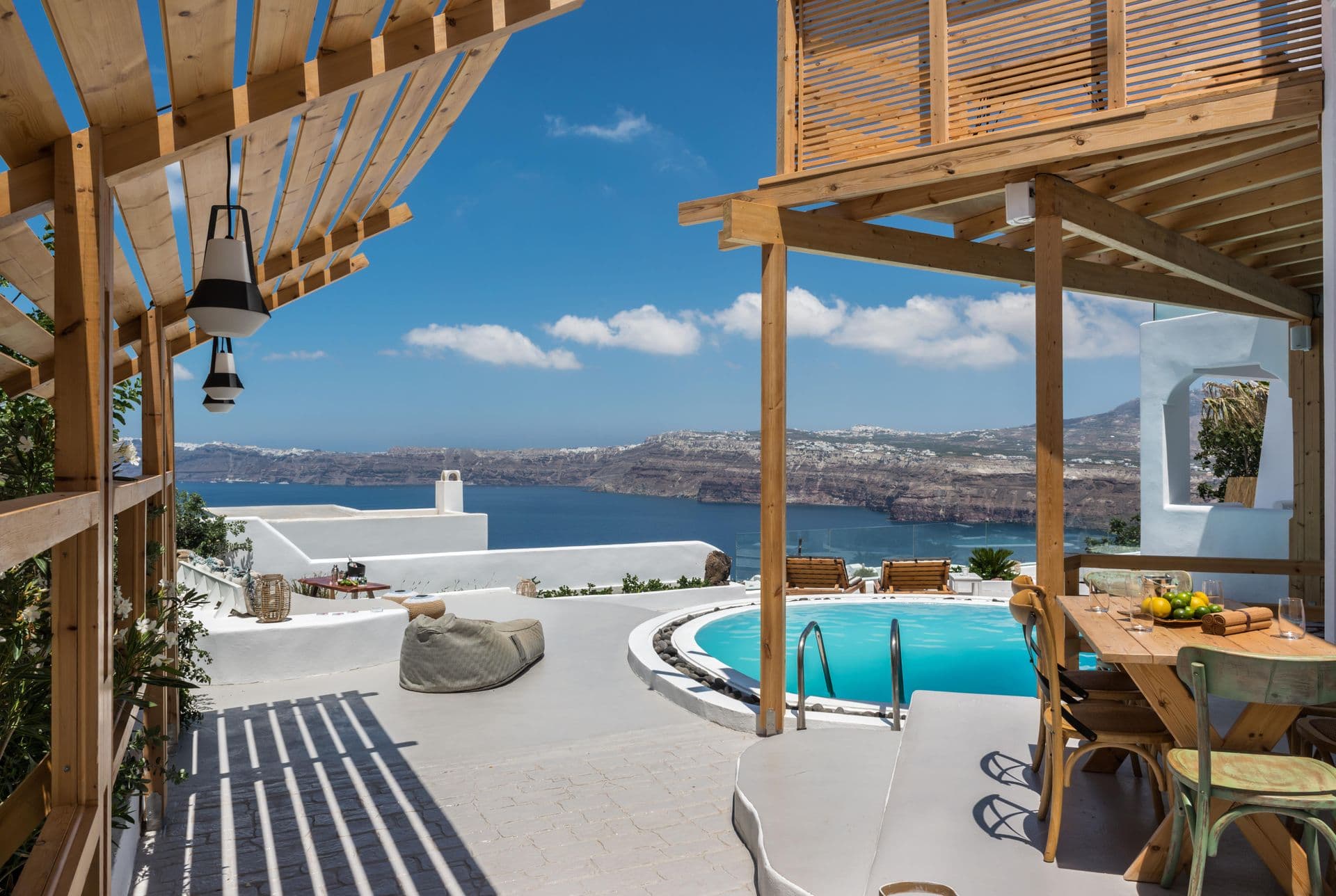 Timber pergola terrace with dining table beside the pool and caldera view at Hand of Hygieia
