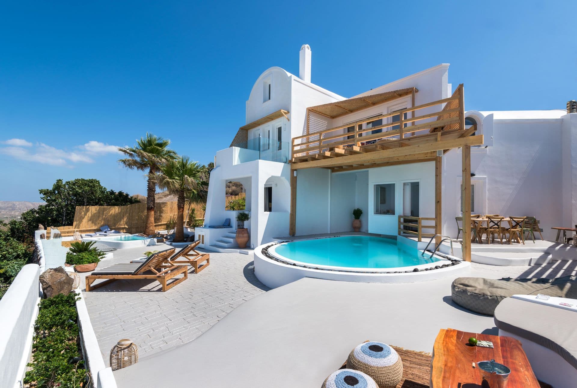 Curved swimming pool on a whitewashed terrace overlooking the Santorini caldera at Hand of Hygieia