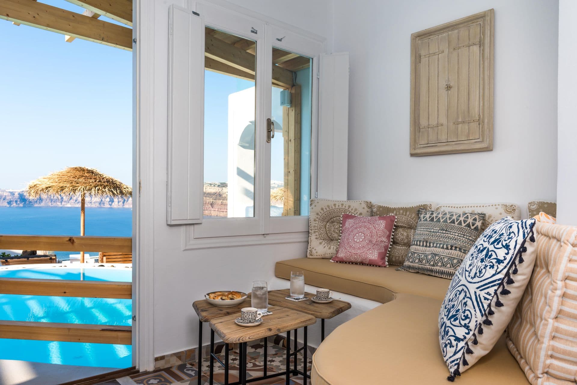 Cushioned sitting nook beside a window with sea and pool view at Hand of Hygieia