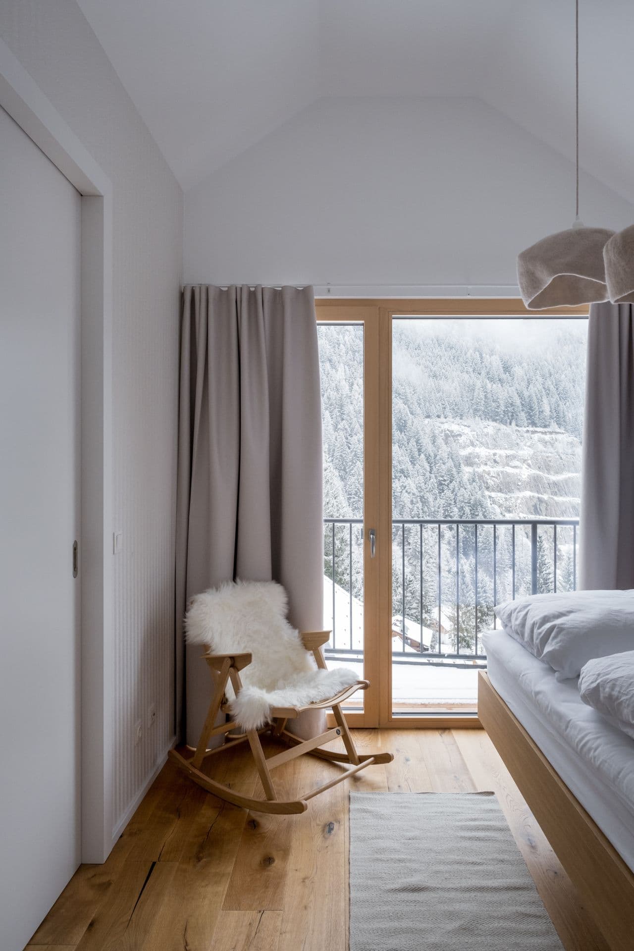 Twin bedroom with rocking chair beside a window opening onto the balcony