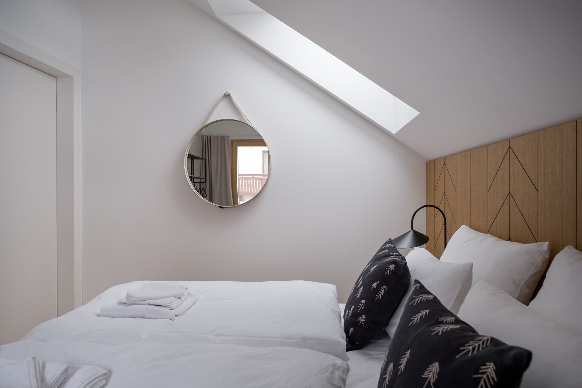 Attic bedroom with sloped ceiling, skylight and round wall mirror