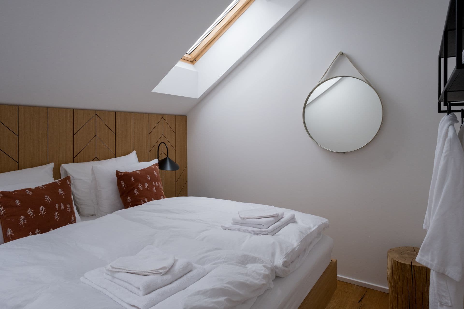 Attic bedroom with skylight, round mirror and red patterned cushions