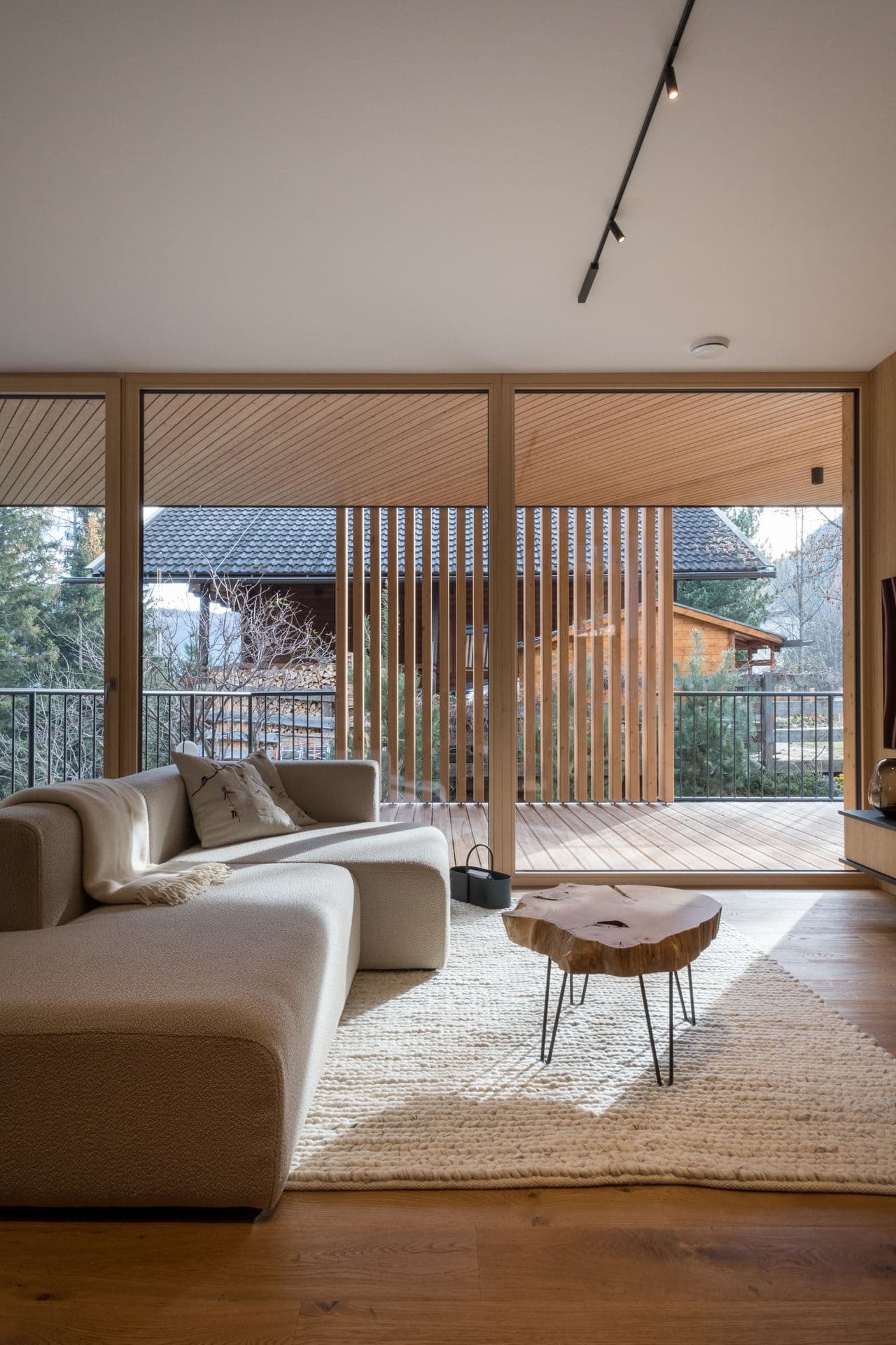 Bright living room with cream sofa, rug and sliding doors onto the chalet exterior