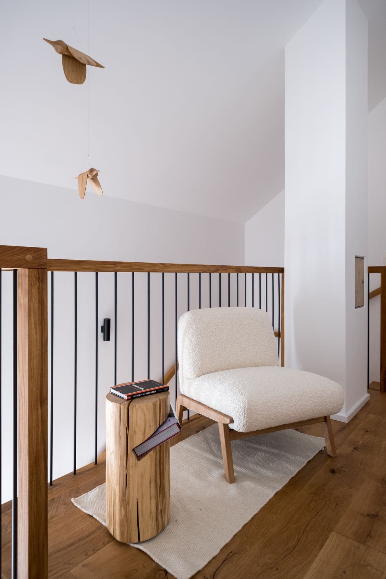 Mezzanine landing with armchair, wood railing and view down the staircase