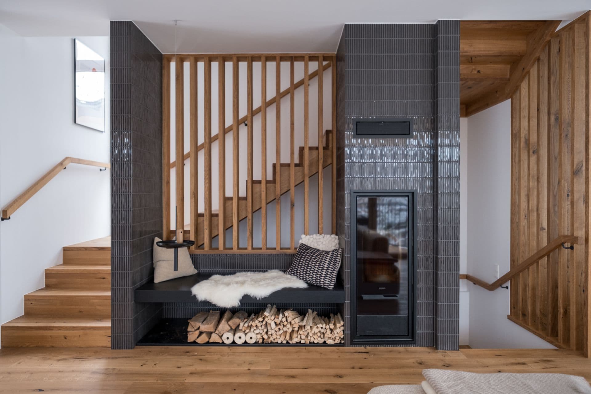 Wooden staircase beside a built-in wood burner with stacked logs and sheepskin throw