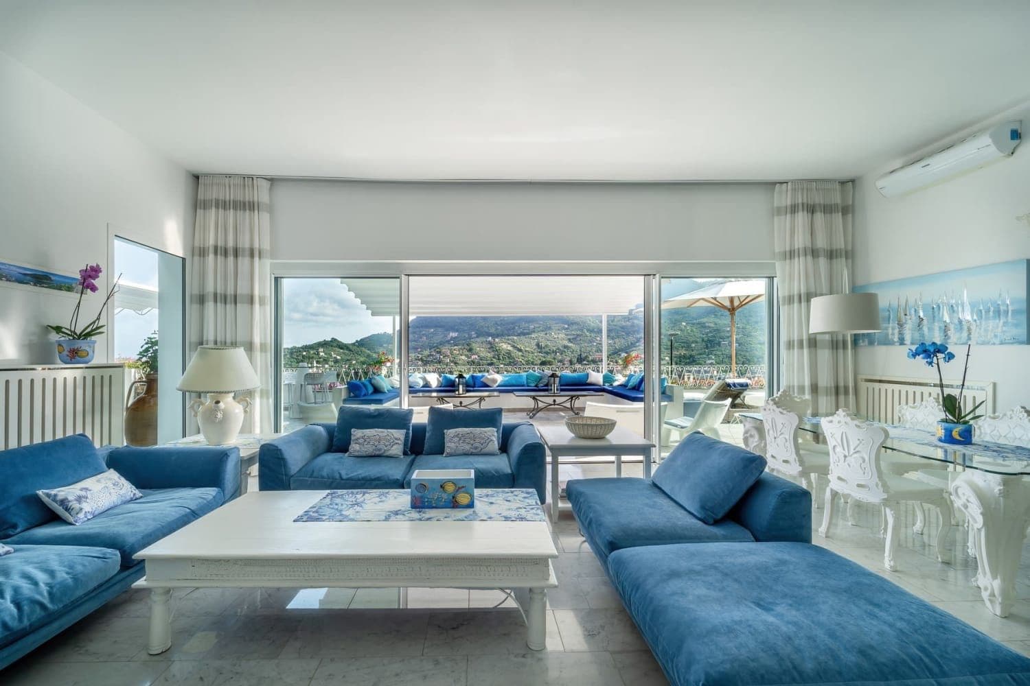 Living room with blue sofas and panoramic hillside windows