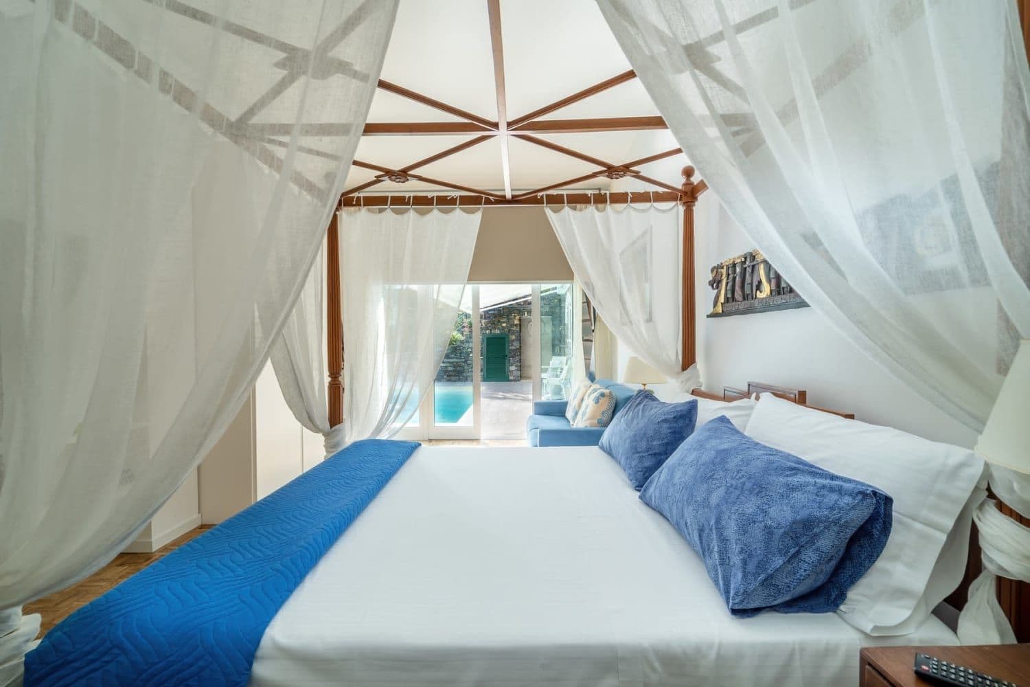 Bedroom with sheer white canopy over a blue-dressed bed