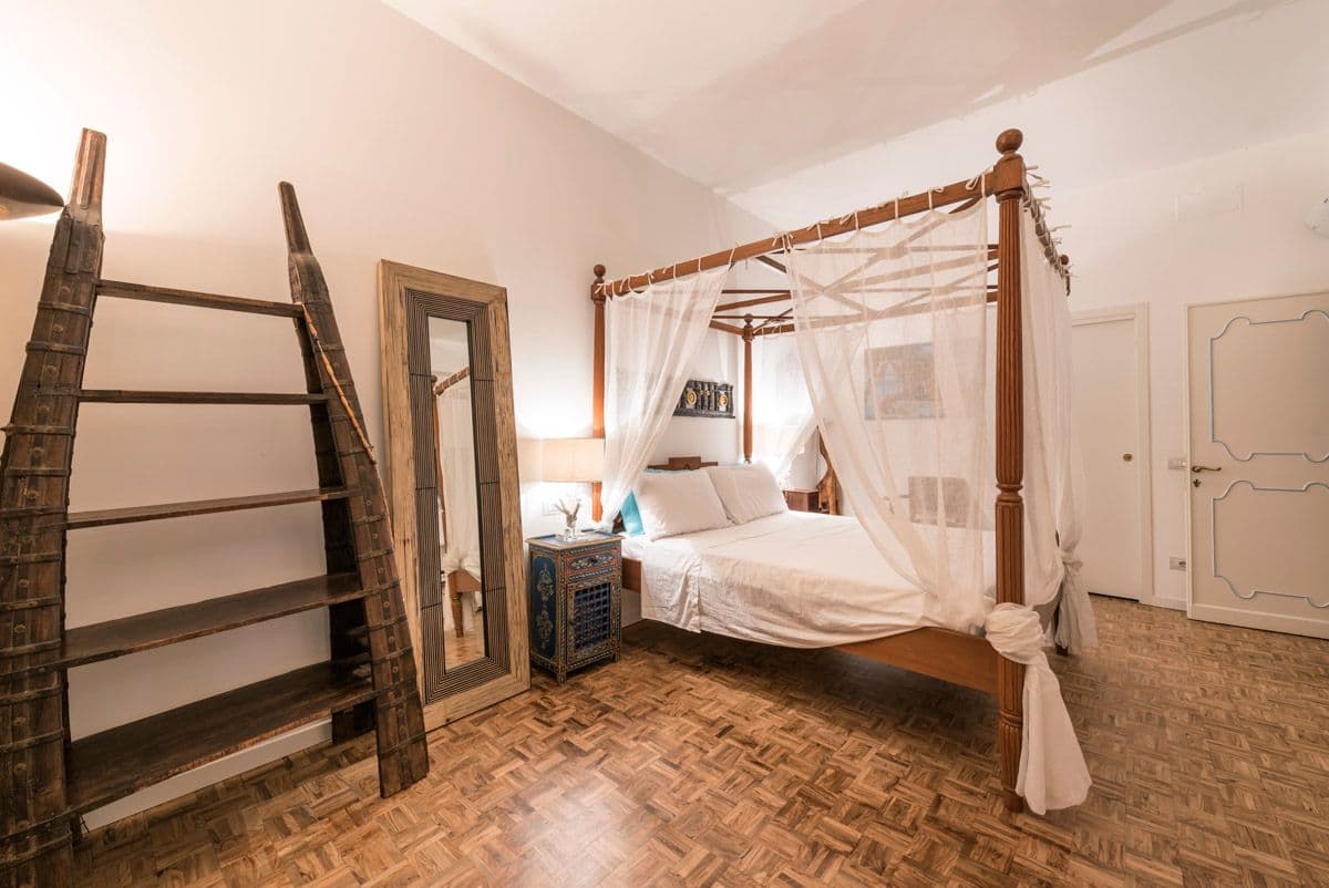 Rustic bedroom with wooden four-poster bed and ladder access