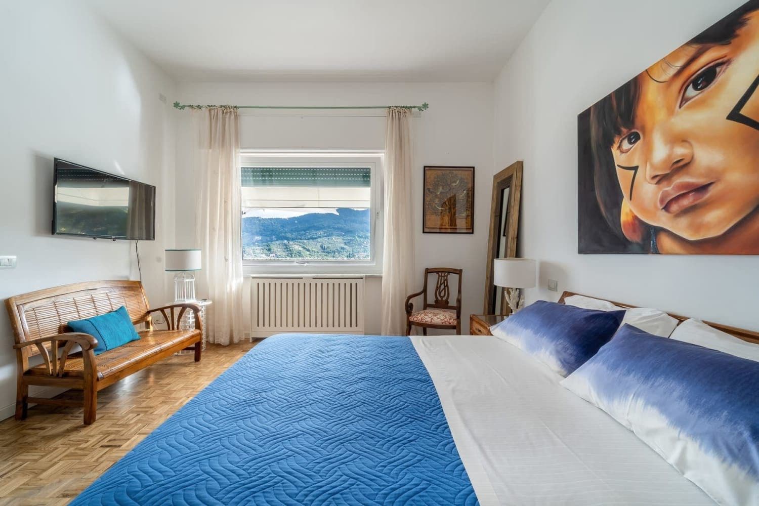 Guest bedroom with blue bedspread and hillside window view