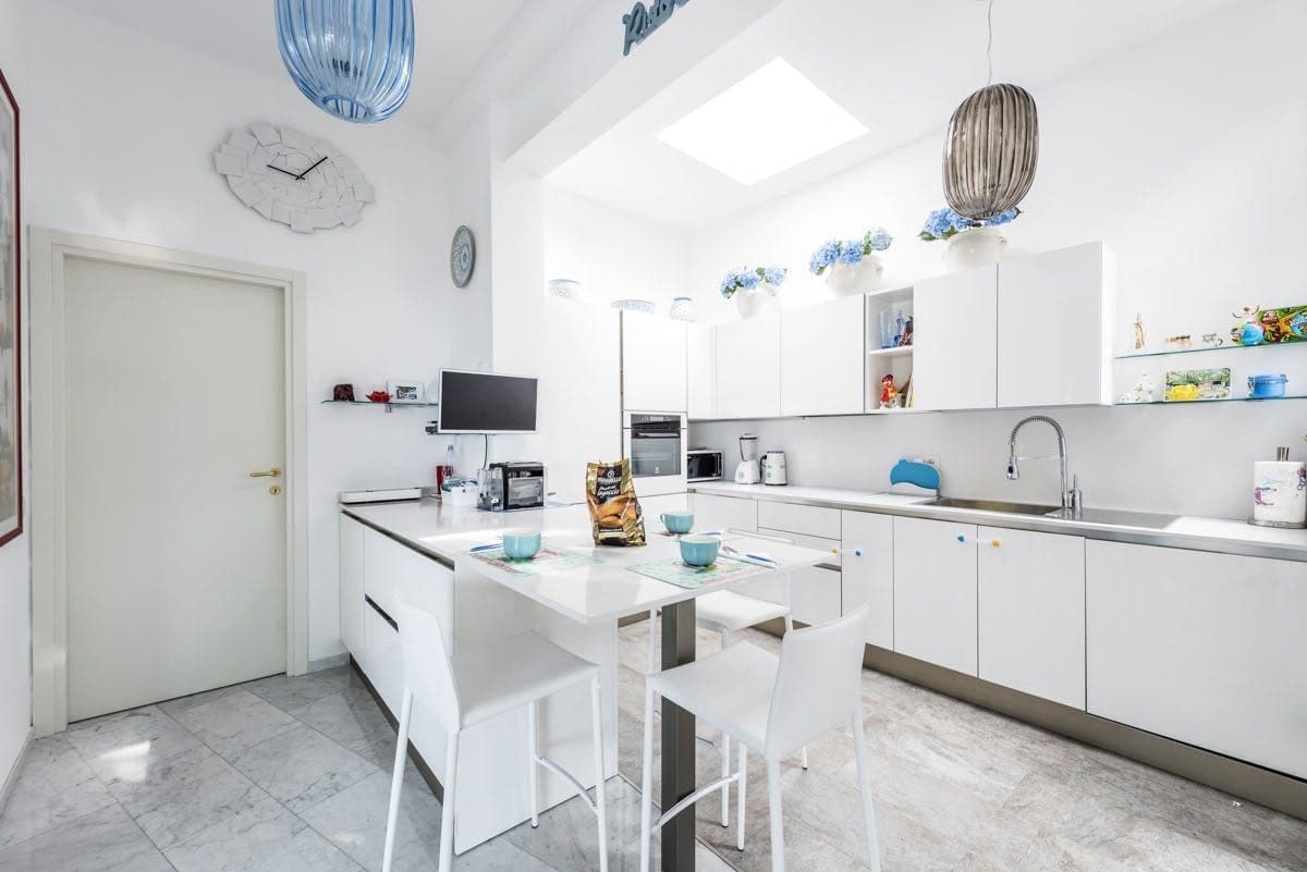 White fitted kitchen with breakfast bar and skylight