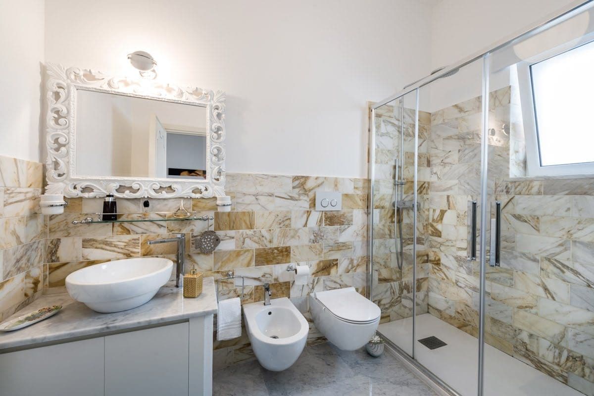 Marble en-suite bathroom with glass shower and vessel sink