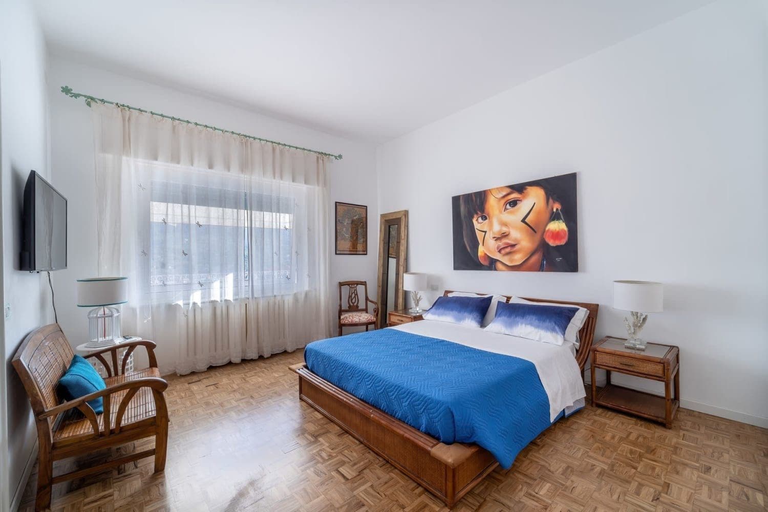 Bedroom with blue bedspread and colourful artwork
