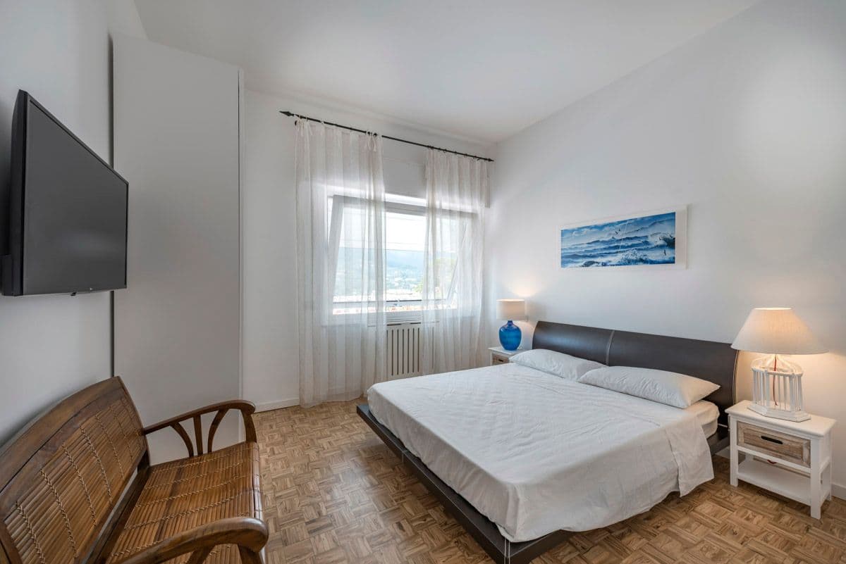 Bedroom with grey upholstered headboard and rattan armchair