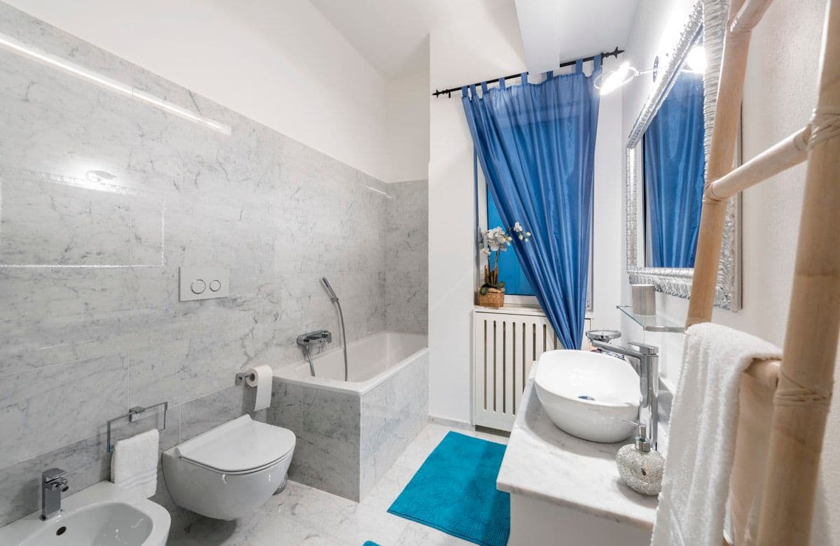 Bathroom with blue shower curtain and marble fittings