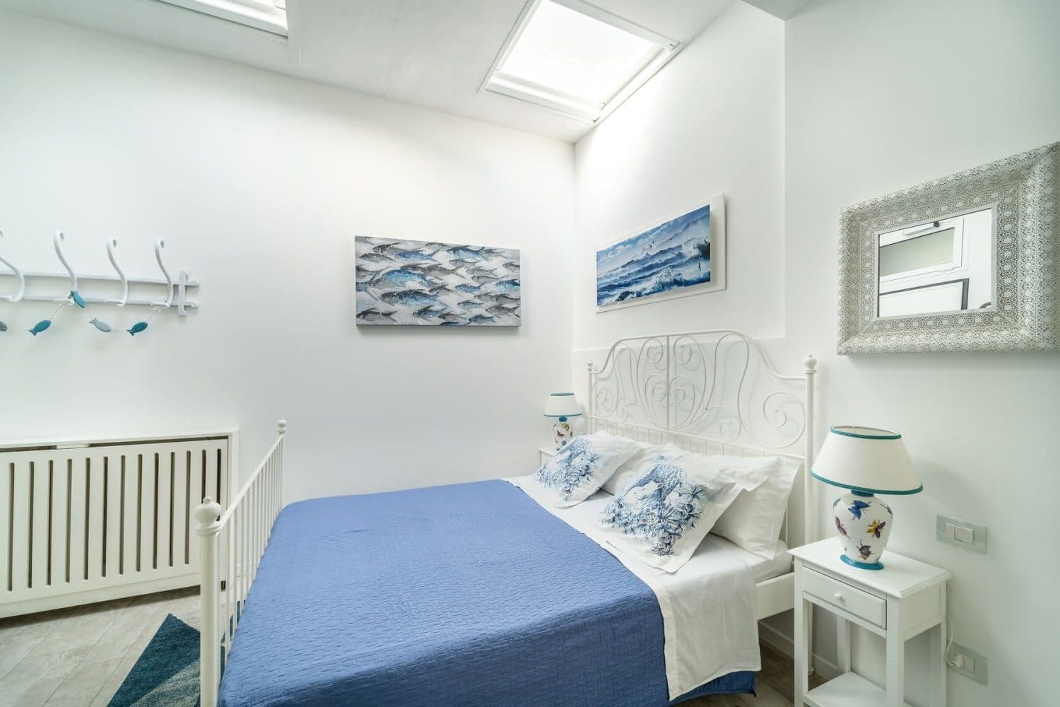 Bedroom with white furniture and blue bedspread beneath a skylight