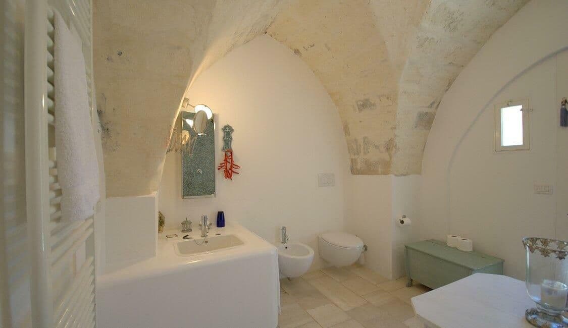En suite bathroom with mosaic tiling and a vaulted alcove