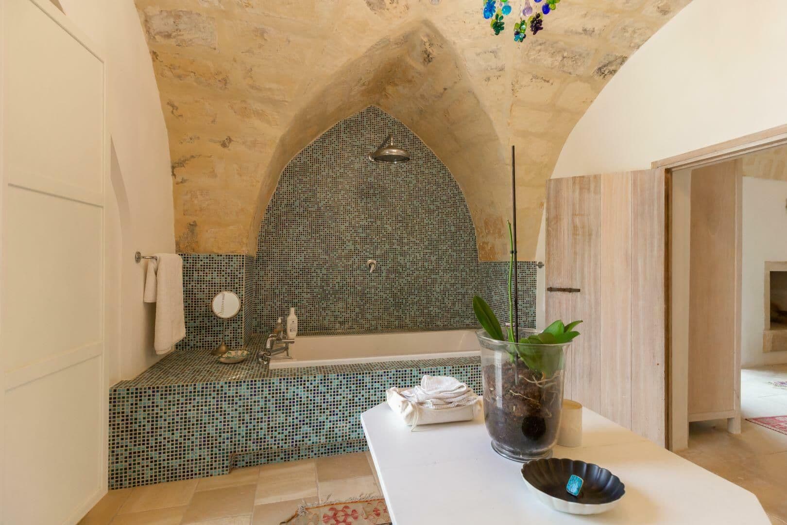 Freestanding bath set beneath a vaulted ceiling with mosaic tiling