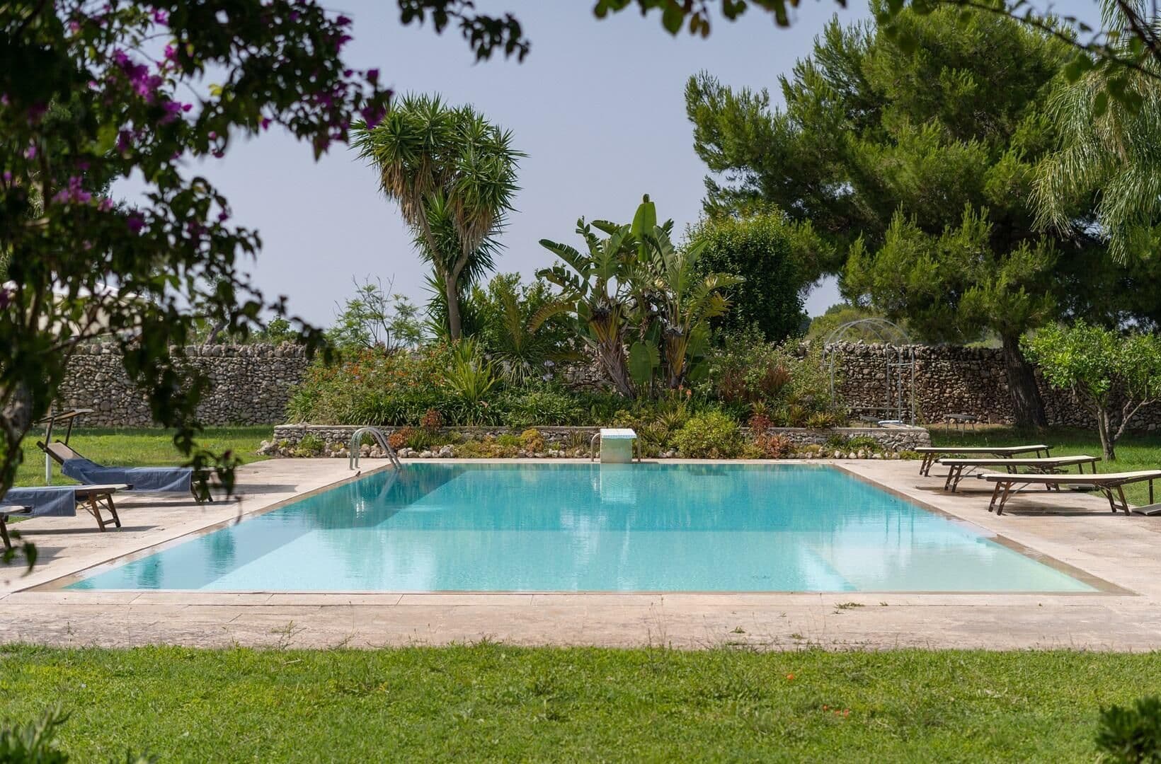 Rectangular pool bordered by lawn and sun loungers