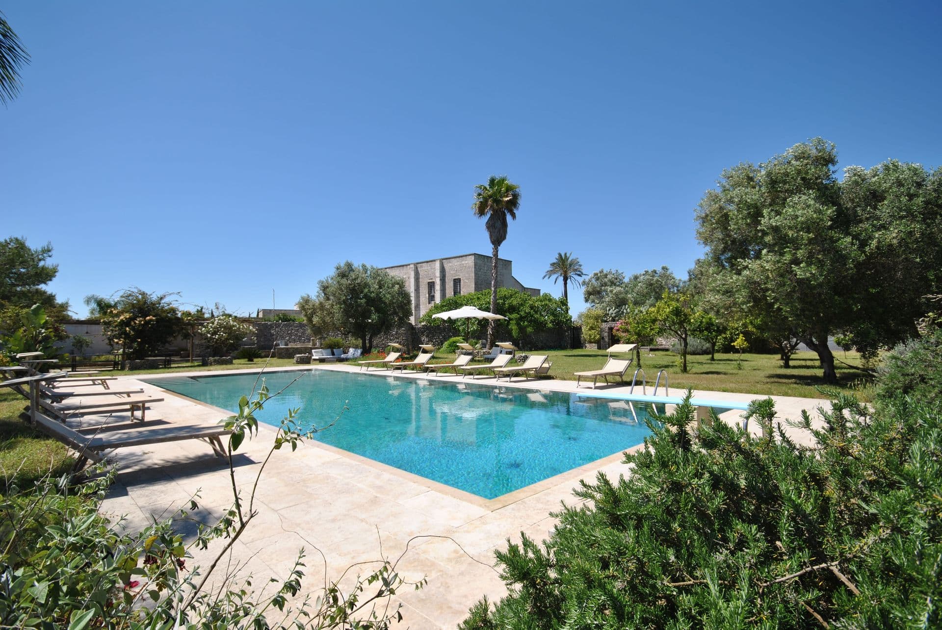 Swimming pool with sun loungers and palm trees at The Wise Soul, a Puglia masseria