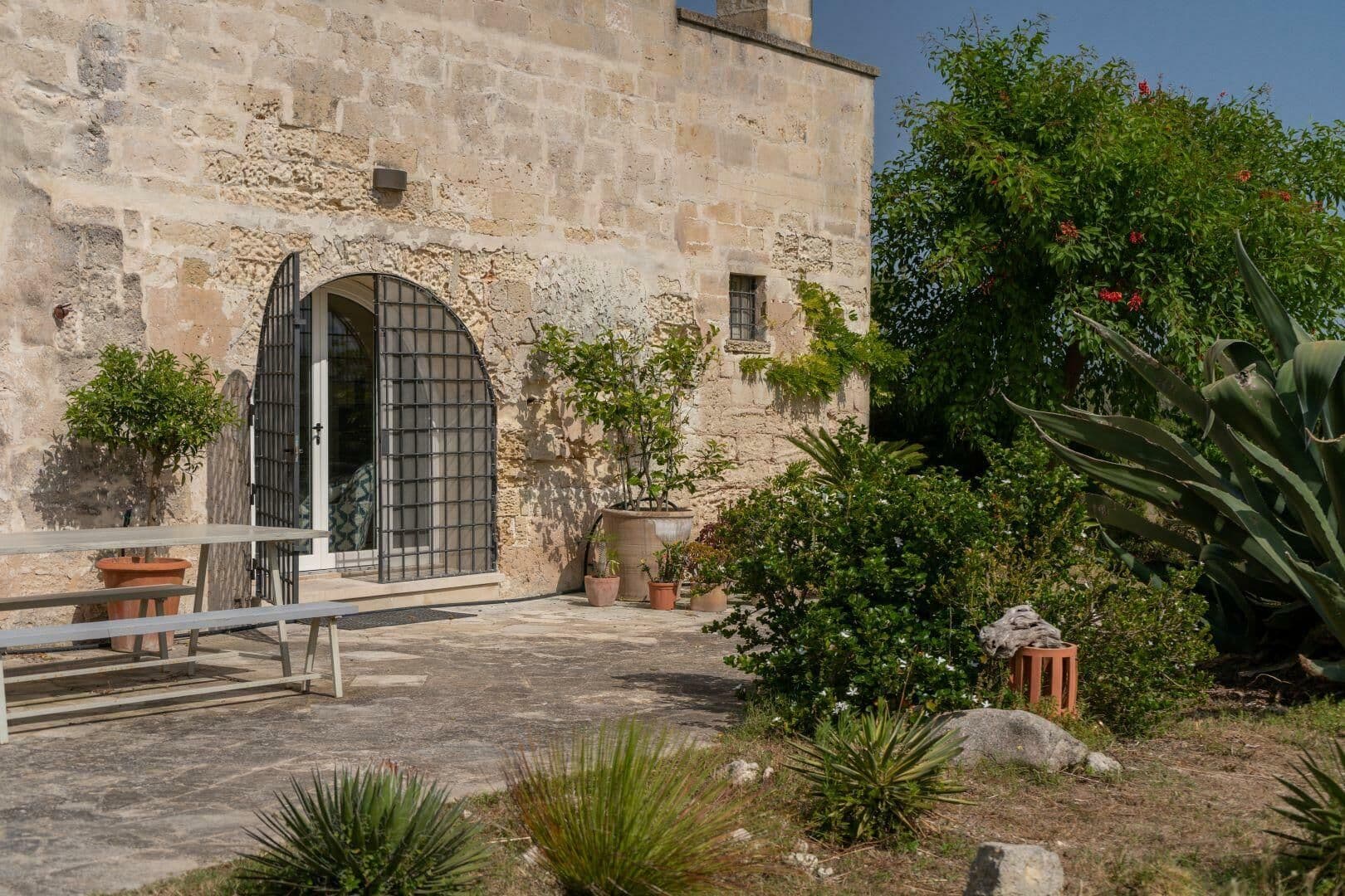 Stone archway entrance to the farmhouse with iron gate and courtyard planting