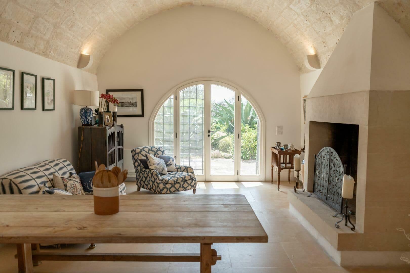 Vaulted living room with a stone fireplace and arched garden doors