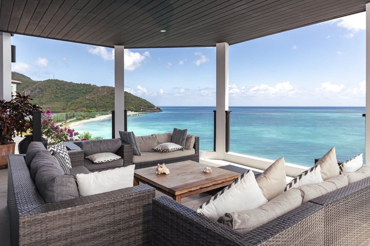 Covered terrace with wicker lounge seating overlooking the sea at Sunlight Breeze, Antigua