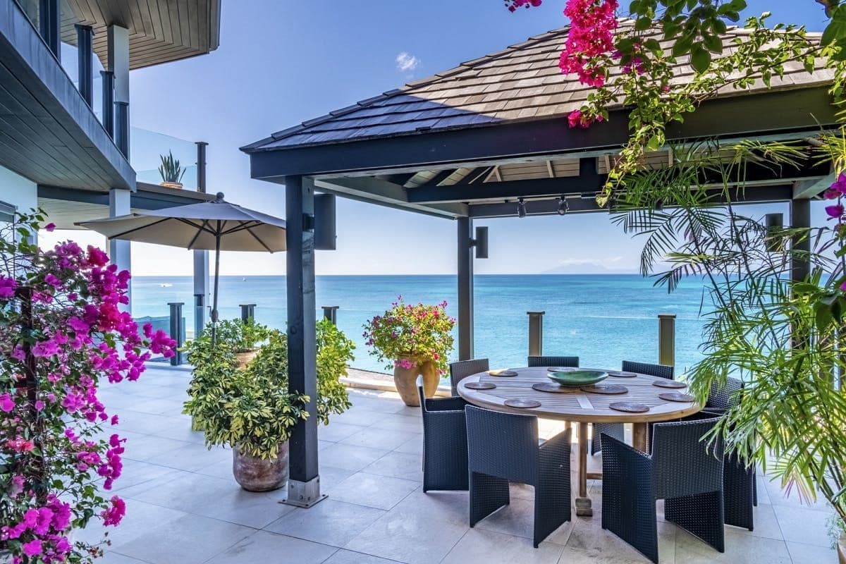 Shaded outdoor dining table framed by bougainvillea over the sea at Sunlight Breeze, Antigua