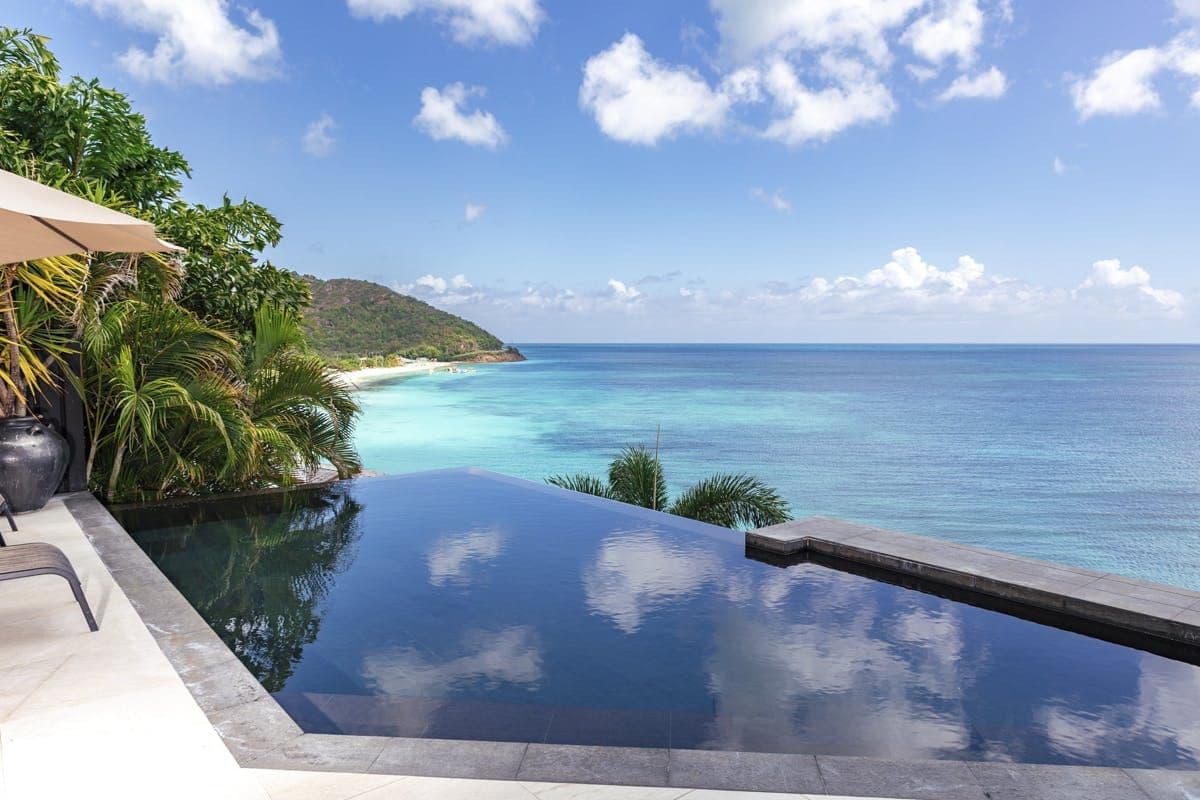 Infinity pool reflecting the sky above the turquoise sea at Sunlight Breeze, Antigua