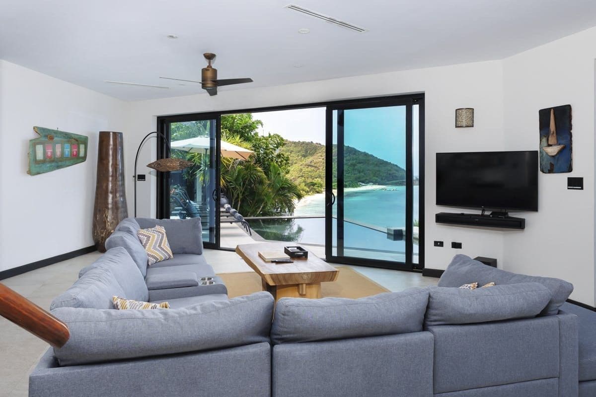 Living room with grey sofas opening to the sea at Sunlight Breeze, Antigua