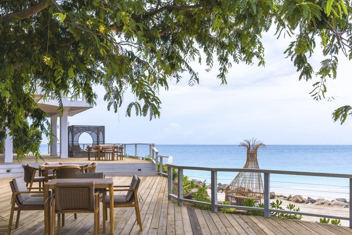 Waterside deck with a dining table above the beach at Sunlight Breeze, Antigua