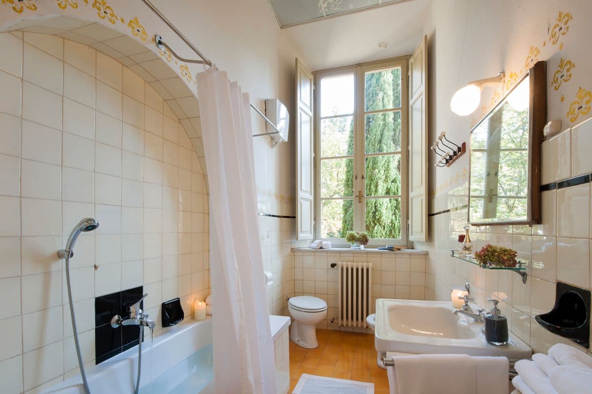 Tiled ensuite bathroom with a bathtub, shower curtain and garden view at Midnight Ball