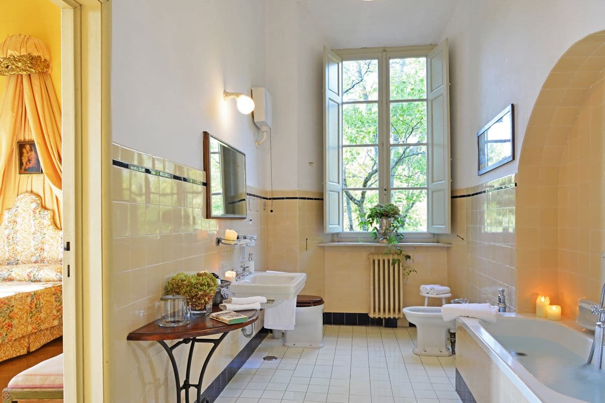 Tiled bathroom with a double vanity, freestanding bath and arched window at Midnight Ball